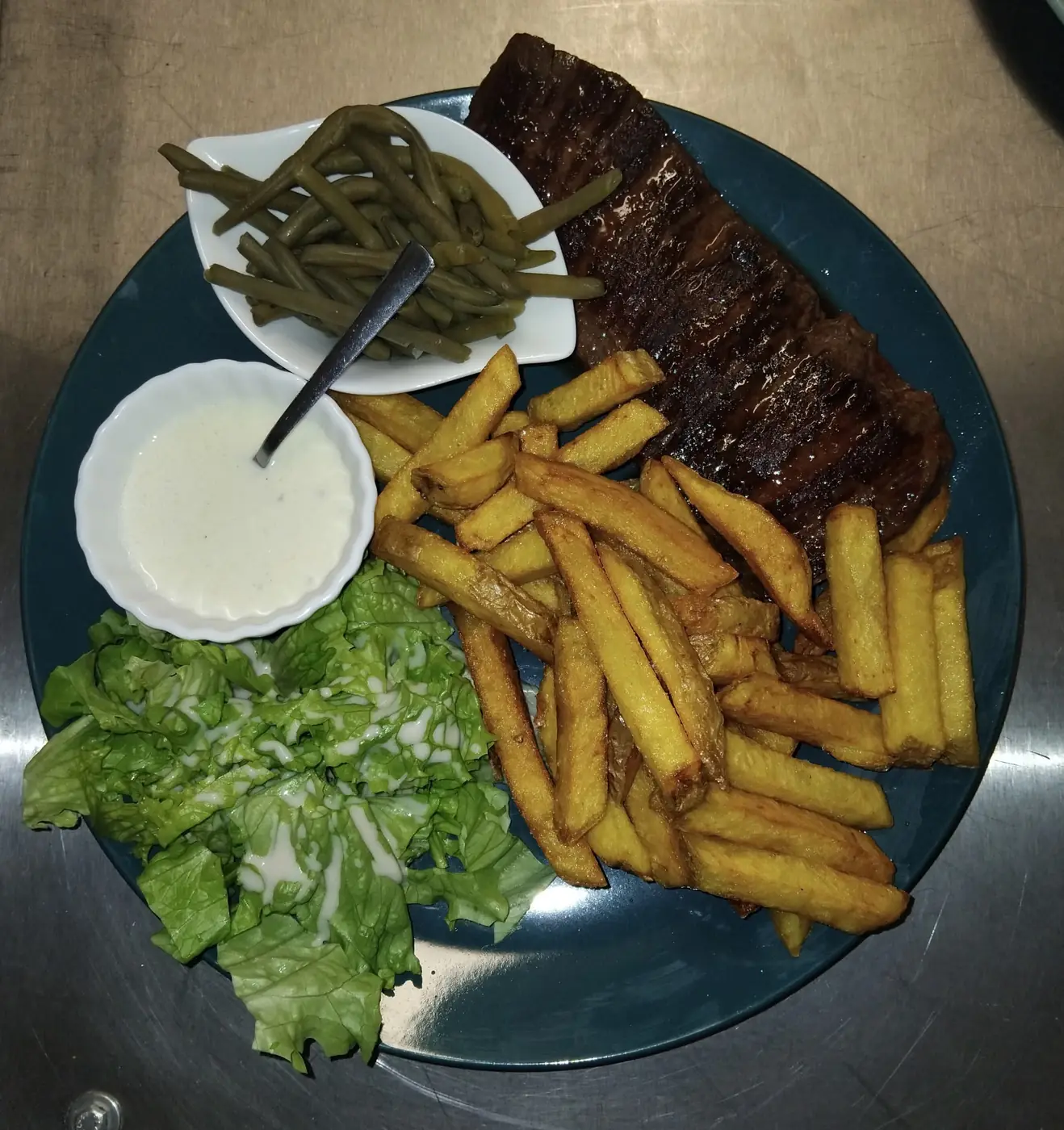 Une assiette généreuse du Café des Artistes : pièce de bœuf, frites maison, haricots verts et salade